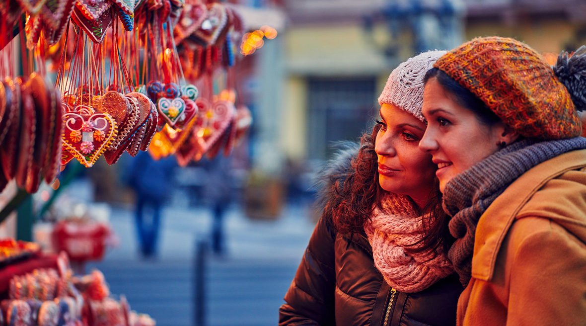 two women in coats and hats looking at beautiful Christmas decorations hanging from market stall